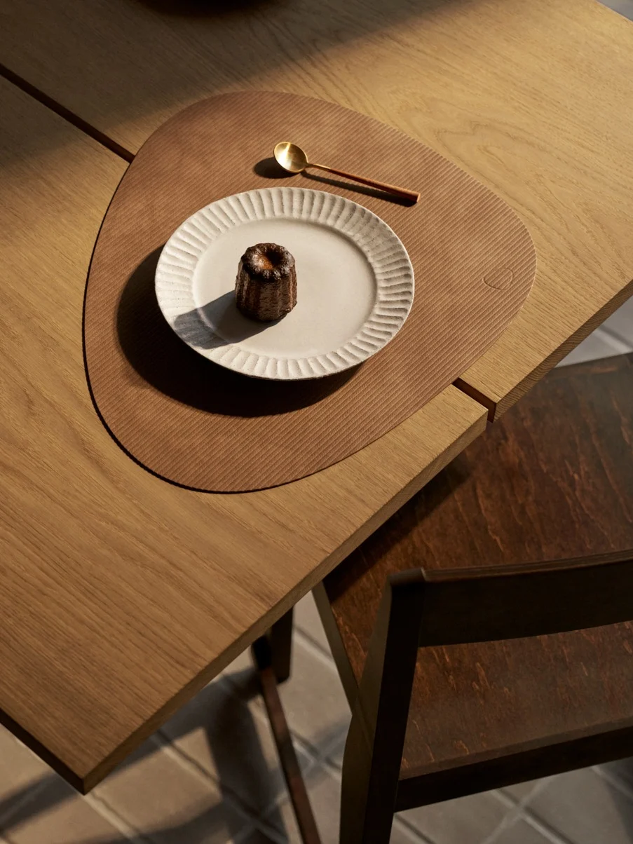 俯视图：白色盘中的可露丽，金色勺子，带纹理的棕色餐垫，木制餐桌。