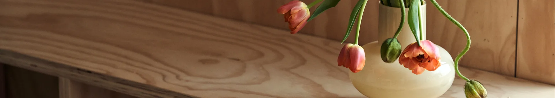 阅读北欧之巢的室内设计技巧和最新设计趋势。图中展示了一只Marimekko的黄色花瓶，里面插着橙色的郁金香。
