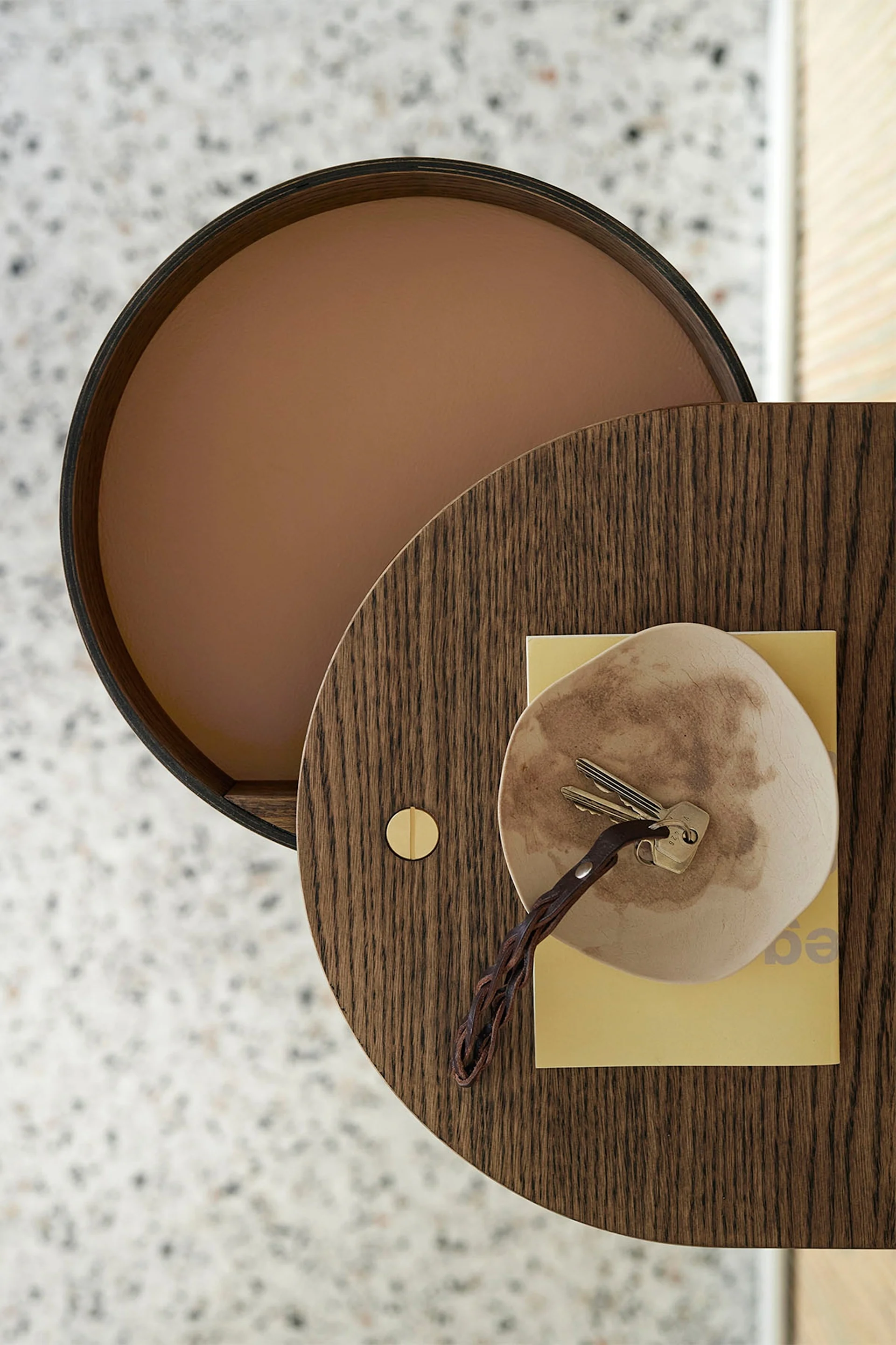 圆形木桌俯视图，桌上有钥匙放在盘子里，旁边有一本黄色书。