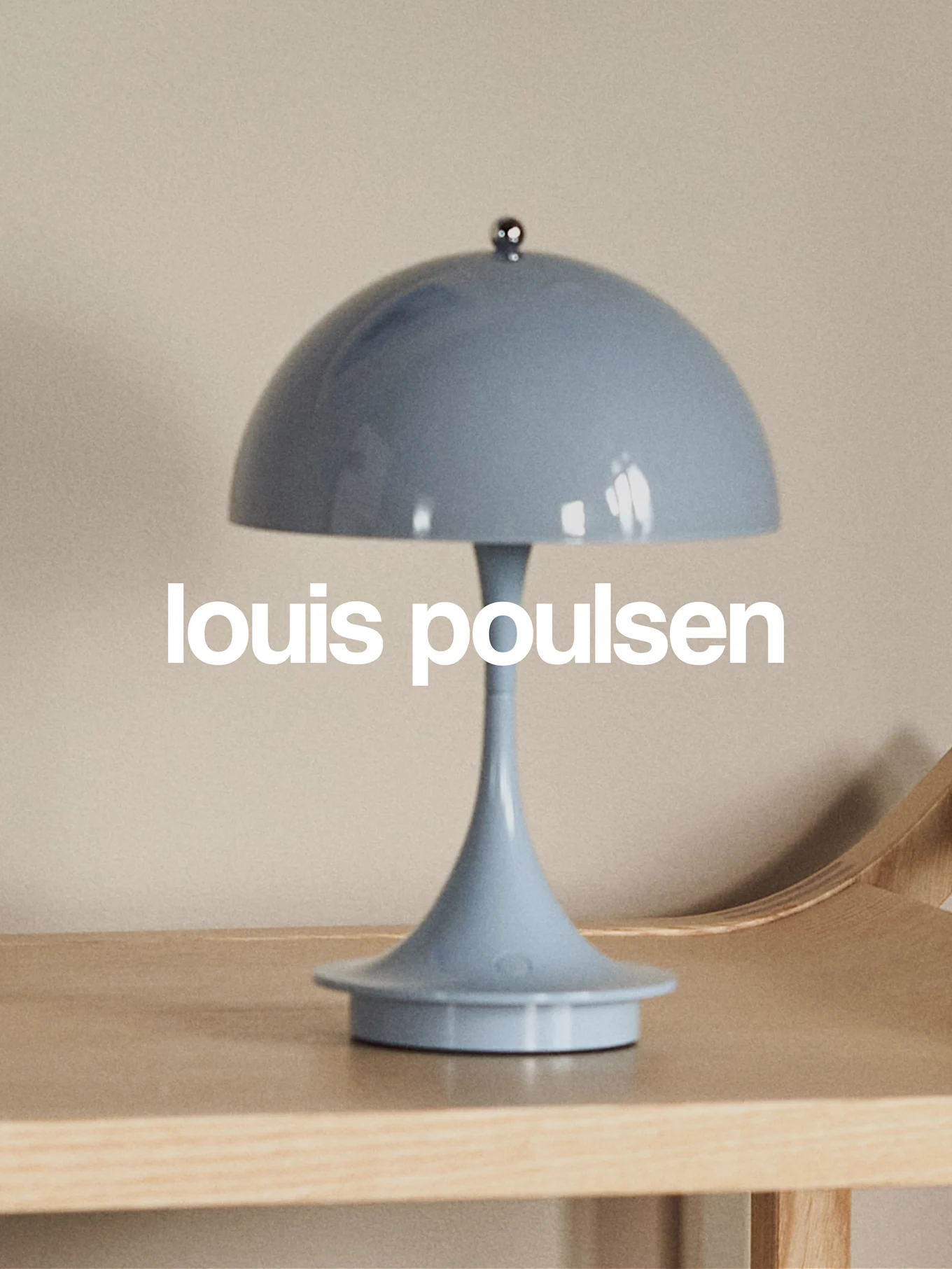 浅蓝色蘑菇形台灯置于木质表面，并带有“louis poulsen”字样。
