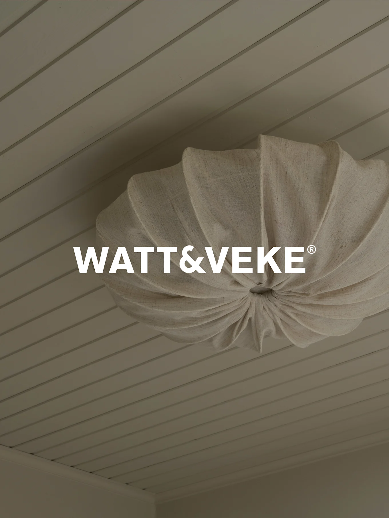 WATT&VEKE®标志，位于浅色木板天花板上，一个褶皱天然织物吸顶灯上方.